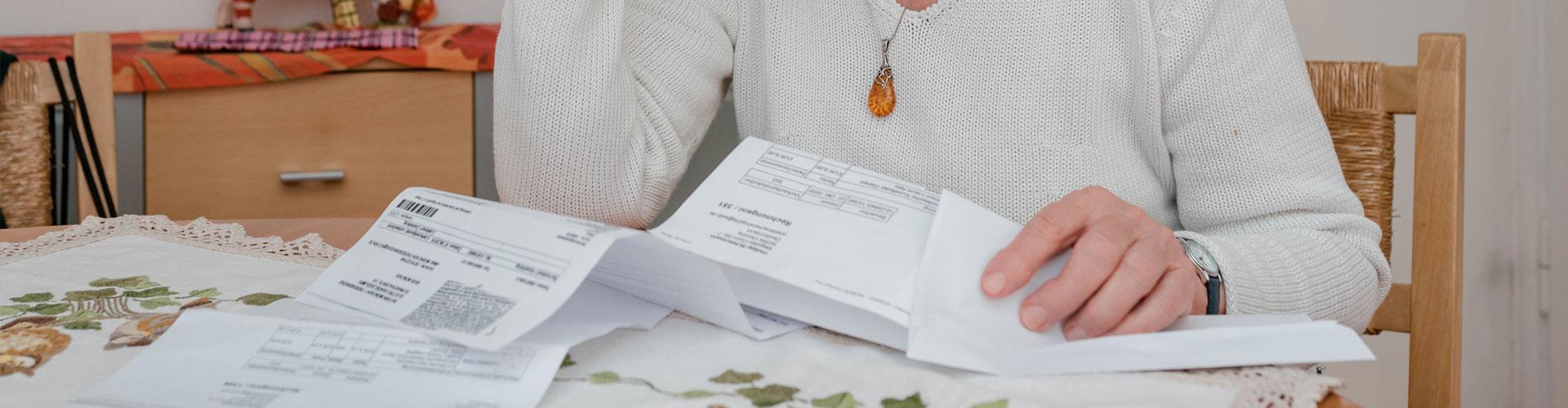 Rentnerin sitzt am Tisch und liest ihren Rentenbescheid
