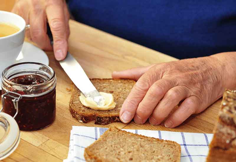 Zoom auf Männerhände, die ein Butterbrot zubereiten.