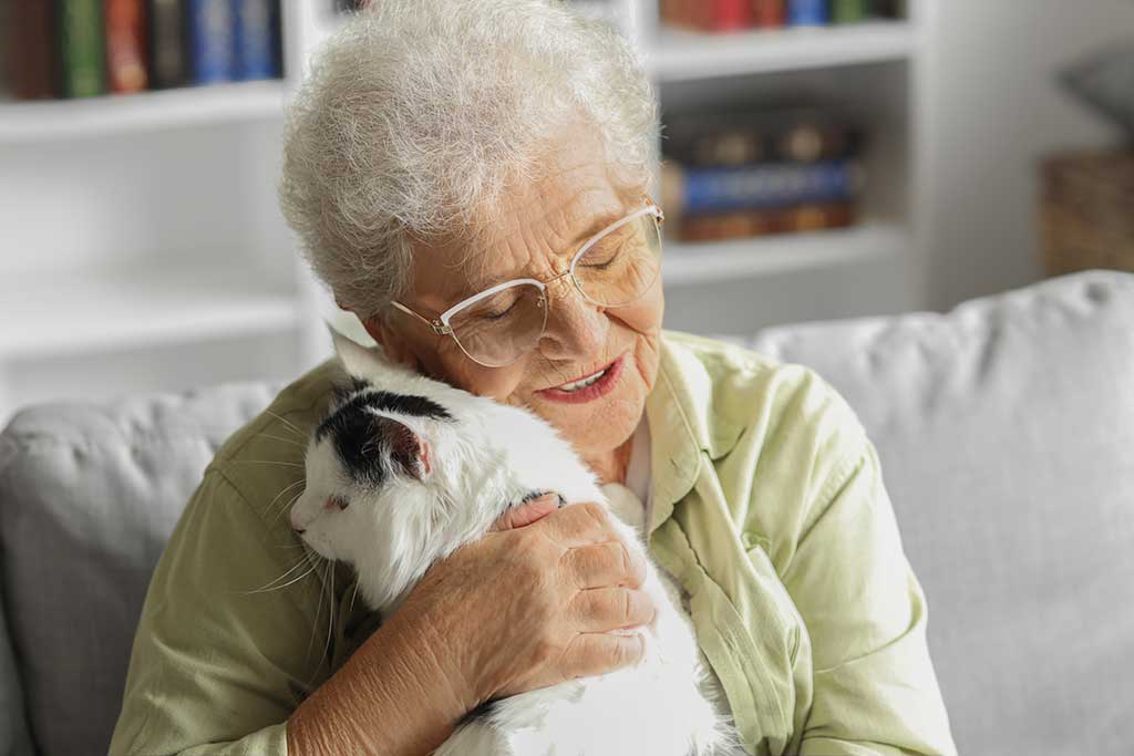 Rentnerin kuschelt mit Katze auf dem Sofa